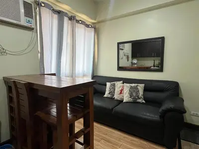 a living room with a black couch and a table at Cozy Staycation at Eastbay Residences in Manila