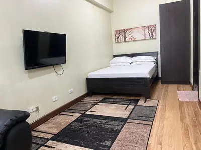 a bedroom with a bed and a flat screen tv at Cozy Staycation at Eastbay Residences in Manila