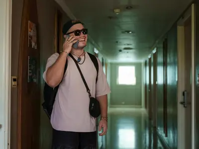 a man standing in a hallway talking on a cell phone at CONNECTOR Hostel in Manila