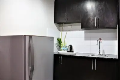 a kitchen with black cabinets and a stainless steel refrigerator at The Studio 18 Residences in Manila