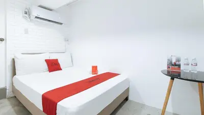 a white bedroom with a bed and a table at RedDoorz Plus at BGC near St Lukes in Manila