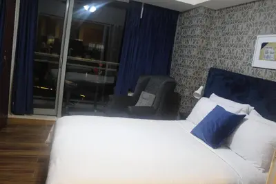a bedroom with a bed and a chair and a window at AZURE C4 BEACHPOOL balcony wifi MULTIPLE UNITS in Manila