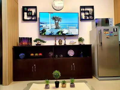 a television on a wall above a cabinet with a refrigerator at Condominium Shore 1 Mall of Asia in Manila