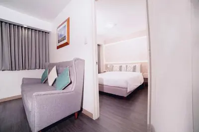 a bedroom with a bed and a chair and a mirror at The Charter House in Manila