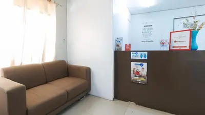 a waiting room with a brown couch and a screen at RedDoorz at Kassel Residences Parañaque in Manila