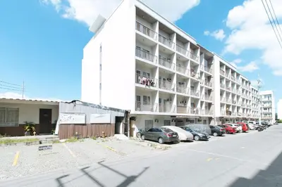 a white building with cars parked in a parking lot at RedDoorz at Kassel Residences Parañaque in Manila