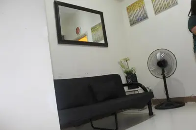 a living room with a black couch and a mirror at CHATEAU ELYSEE a3 near airport Wifi Kitchen in Manila