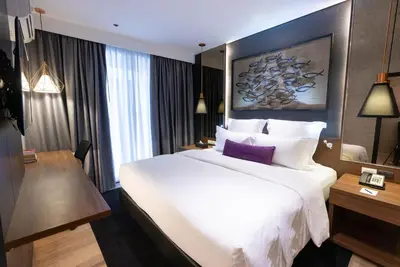 a hotel room with a large white bed and a desk at Coro Hotel in Manila