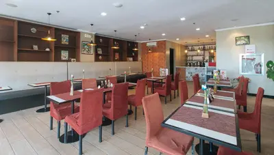 a restaurant with wooden tables and red chairs at RedDoorz Plus at MM Hotel Las Pinas former RedDoorz Plus Near Bamboo Organ in Manila