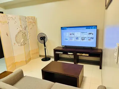 a living room with a couch and a flat screen tv at ONE UPTOWN RESIDENCES in Manila