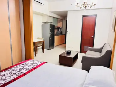 a room with a bed and a chair and a kitchen at ONE UPTOWN residence SW14M 9TH AVENUE ST \u516c\u5bd3 in Manila