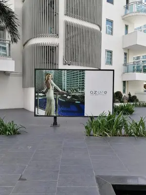 a sign in front of a building with a picture of a woman at AZURE Urban Resort Residences 1BR Condo with huge wavepool & man-made beach near Airport in Manila