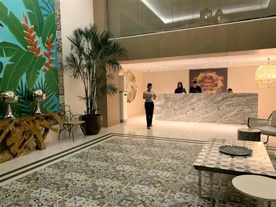 a woman walking down a hallway in a building at AZURE Urban Resort Residences 1BR Condo with huge wavepool & man-made beach near Airport in Manila
