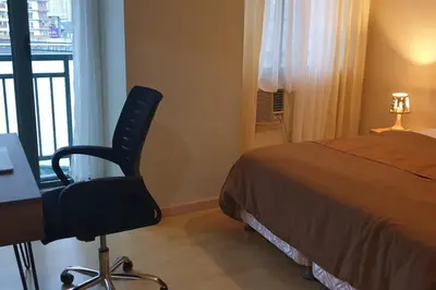 a bedroom with a bed and a desk and a chair at MANDALUYONG 2 Br w 2 Queen, 50HDtv across Shangrila Mall in Manila