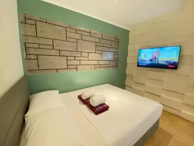 a bedroom with a white bed and a flat screen tv at The Hub District Garden Suites in Manila