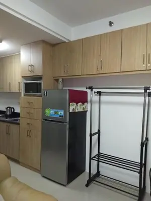 a kitchen with a stainless steel refrigerator and wooden cabinets at Jones Shore Residences in Manila