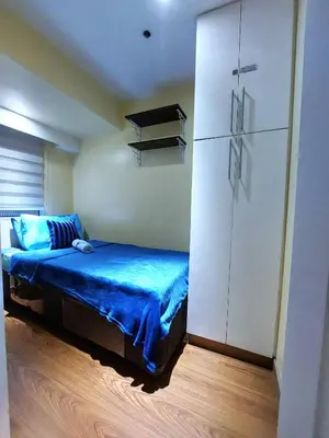 a bedroom with a bed and a white cabinet at Fort Victoria BGC 2 Bedrooms in Manila