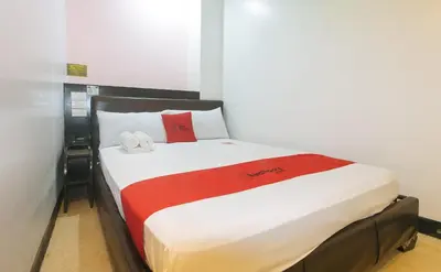 a bedroom with a bed with red and white sheets at RedDoorz at Ranchotel Alabang in Manila