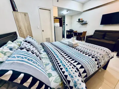a bed with pillows on it in a living room at One Palm Tree Villas across NAIA-T3 in Manila