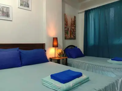 two beds in a room with blue pillows on them at Jen's Apartment in Manila