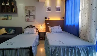 two twin beds in a room with a couch at Jen's Apartment in Manila