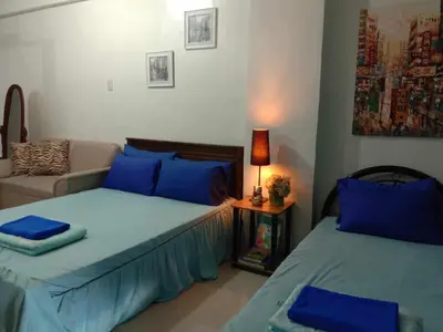 a bedroom with two beds and a couch at Jen's Apartment in Manila