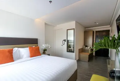 a bedroom with a large white bed with orange pillows at Privato Makati in Manila