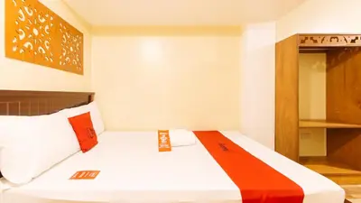 a bedroom with a bed with orange and white pillows at RedDoorz near PNR Espana Station in Manila