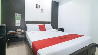 a bedroom with a large bed with a red blanket at RedDoorz at Ranchotel Bayanan Alabang in Manila