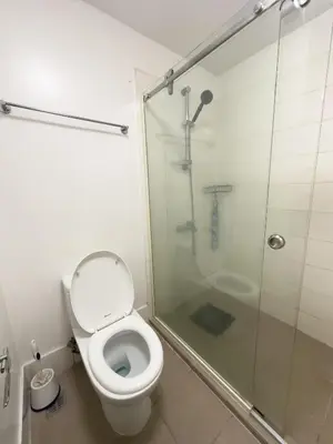 a bathroom with a toilet and a glass shower at StayHere BGC City Studio in SOMA near SM Aura in Manila