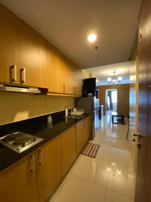 a kitchen with wooden cabinets and a black counter top at Cozy Space at Shell Residences in Tower A in Manila