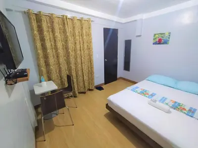 a bedroom with a bed and a tv and a table at JB Valdres Apartment in Manila