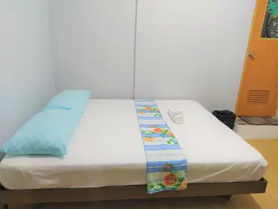 a bed with white sheets and blue pillows at JB Valdres Apartment in Manila