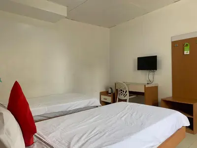 a room with two beds and a desk and a television at Lucky Hotel Binondo in Manila