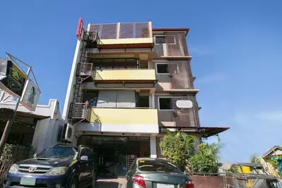 a tall building with cars parked in front of it at Rjat Guesthouse in Biñan