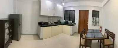 a kitchen with white cabinets and a table and chairs at Matchi in Manila