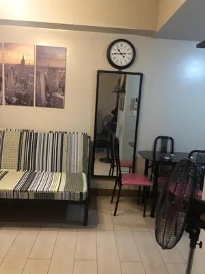 a room with a couch and a clock on the wall at Favila Condotel unit in Palmtree Villas Newport City walking distance to Airport terminal 3 Accessable to Airport terminal 1 &2 in Manila