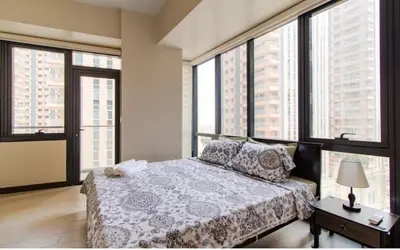 a bedroom with a bed and large windows at Madisons Crib at The Florence in Manila