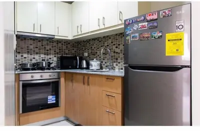 a kitchen with a stainless steel refrigerator and wooden cabinets at Madisons Crib at The Florence in Manila
