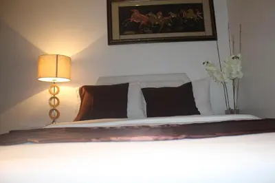 a bedroom with a bed with a lamp and a painting at AZURE C1 with balcony wifi MULTIPLE UNITS near airport in Manila