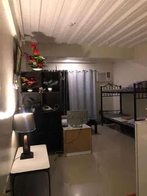 a room with two bunk beds and a desk with a lamp at Your City•Home Apartment in Manila