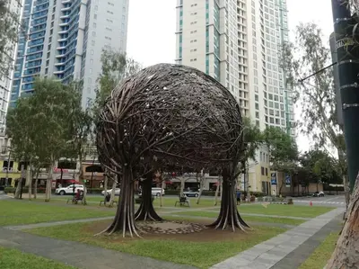 a sculpture of a tree in a park with buildings at StayHere Burgos Circle 1 Bedroom Avant@Fort Gym in Manila