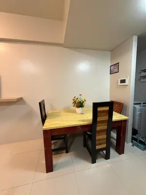 a wooden table with two chairs and a vase of flowers on it at Apartments across NAIA Terminal 3 in Manila