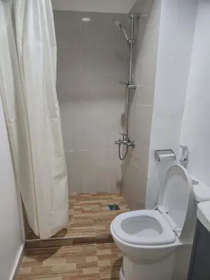 a bathroom with a toilet and a shower with a shower curtain at POBLACION SUITES - Polaris in Manila