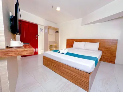 a bedroom with a bed with a red door and a television at Circuit Hostel in Manila