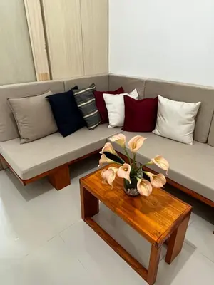 a living room with a couch with pillows and a table at 1BR Jazz Bel-air Makati, POOLVIEW, TRIDENT in Manila