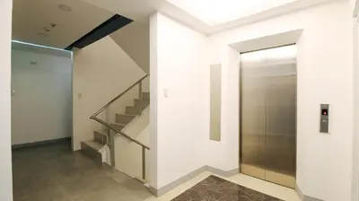 a hallway with a staircase and a glass elevator at RedDoorz Plus @ San Marcelino Malate in Manila