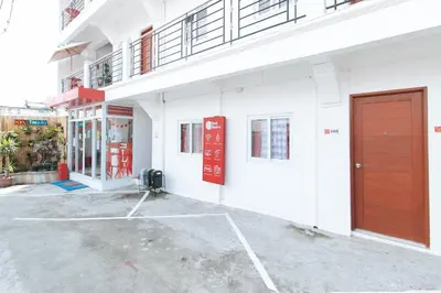 a white building with a red door on the side at RedDoorz near Mercado del Lago in Manila