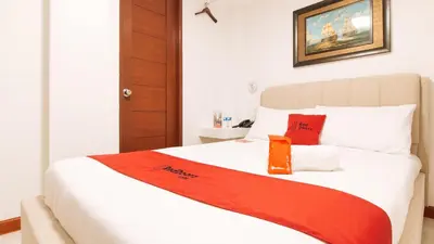 a bedroom with a bed with a red blanket on it at RedDoorz near Mercado del Lago in Manila
