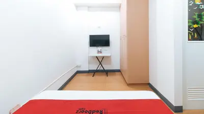 a room with a bed and a desk with a television at RedDoorz at CAA Road Las Pinas in Manila